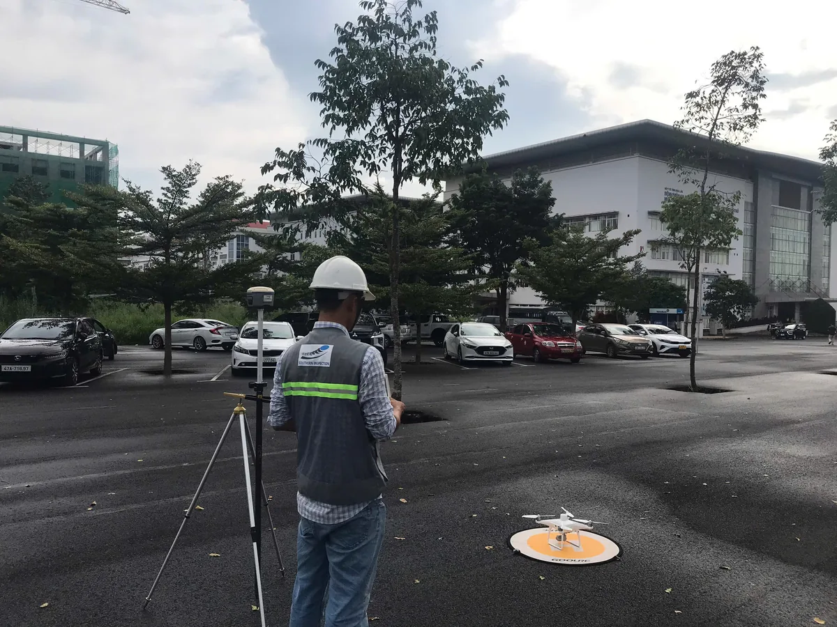 Kỹ sư đang thực hiện đánh giá an toàn công trình bằng thiết bị đo đạc và drone